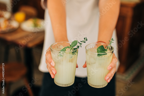 Woman holding non-alcoholic beverage, cold lemonade with mint and ice