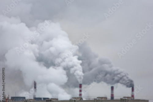 industrial chimneys with heavy smoke causing air pollution on the gray smoky sky background