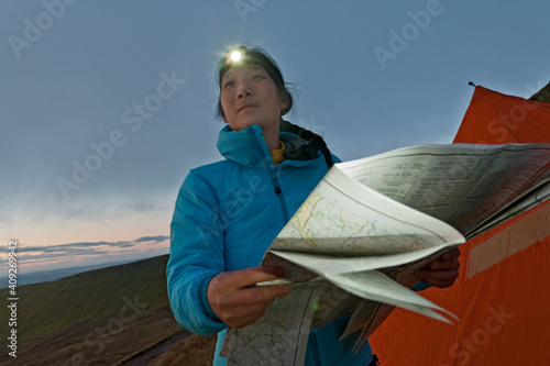female hiker reading hiking map on Pen Y Fan in Wales at sunrise photo
