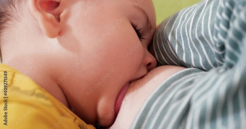 Mother breastfeeding her newborn baby on sofa. Milk from mother's breast is a natural medicine to baby. family, food, child, eating and parenthood concept Mother breastfeeding her newborn baby on sofa. Milk from mother's breast is a natural medicine to baby. family, food, child, eating and parenthood concept