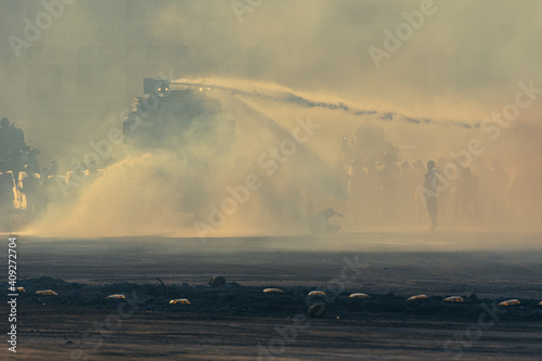 Riot or protest with military vehicle hosing protesters and riot police prepare to take military action. photo