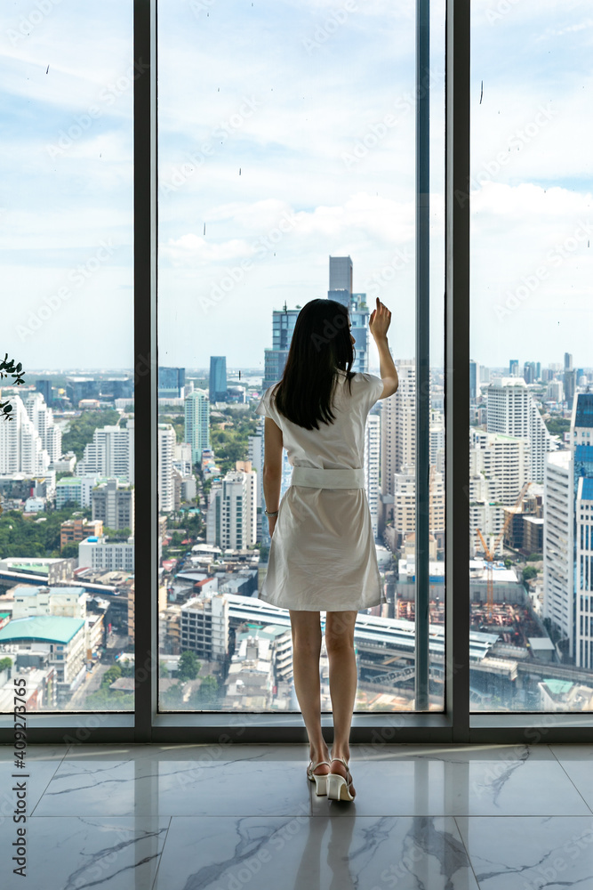 Obraz premium Young stylish beautiful woman in a skyscraper in the office against the background of the window, high floor