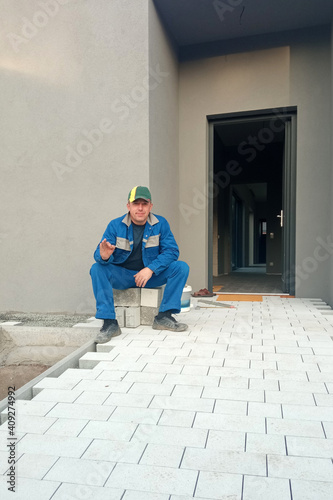 The master lays paving stones for the sidewalk and yard path. © Niko_Dali