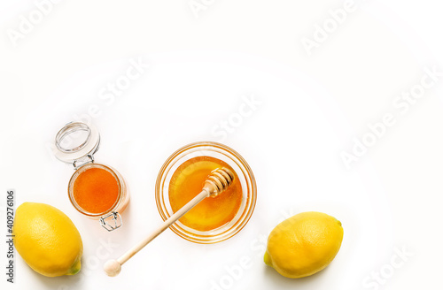 Glass jar and saucer with honey and lemons isolated on white background.