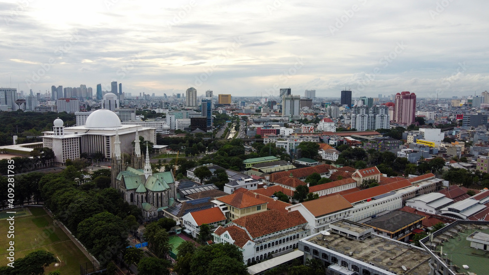 Aerial view of Jakarta cathedral and Istiqlal Mosque. It is the largest mosque in Southeast Asia and noise cloud with Jakarta cityscape. JAKARTA - Indonesia. January 30, 2021