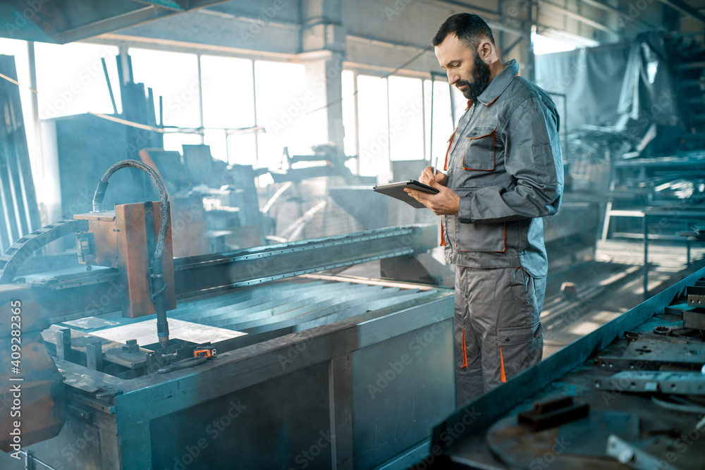 Heavy industry worker controlling the process of metal cutting Heavy industry worker controlling the process of metal cutting