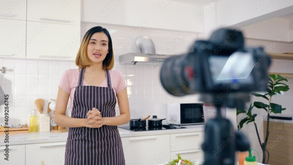 Blogger pastry chef makes a video lesson about cooking a salad. young woman in an apron at home in the kitchen tells the recipe on camera. Online broadcast, author leads a blog or course about cooking Blogger pastry chef makes a video lesson about cooking a salad. young woman in an apron at home in the kitchen tells the recipe on camera. Online broadcast, author leads a blog or course about cooking