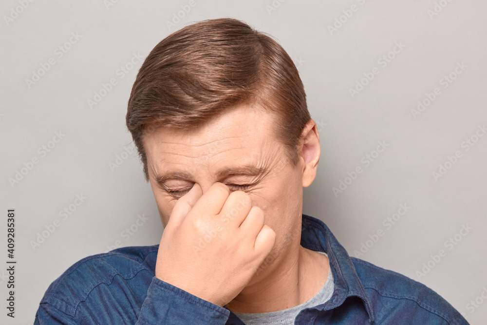 Portrait of unhappy tired man touching bridge of nose, squinting eyes Portrait of unhappy tired man touching bridge of nose, squinting eyes