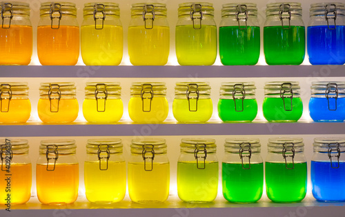 Multi-colored jars with transparent liquid. Multicolored water, Shots with multicolored alcohol, standing in a row.