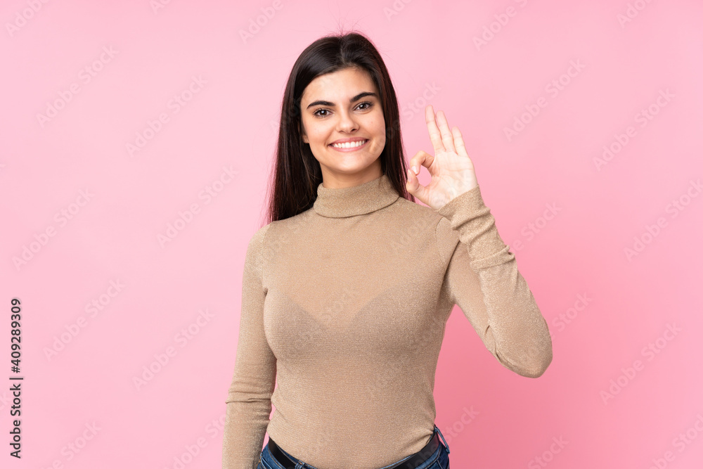 Young woman over isolated pink background showing ok sign with fingers