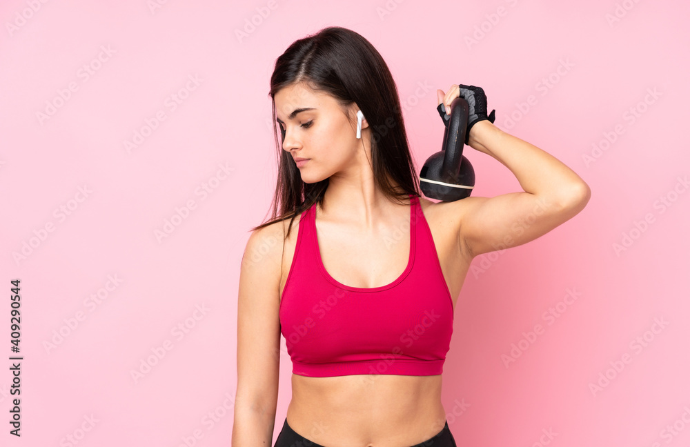 Young sport woman over isolated pink background making weightlifting with kettlebell Young sport woman over isolated pink background making weightlifting with kettlebell