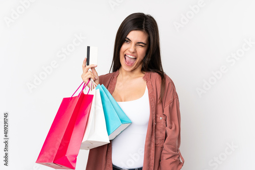 Young woman over isolated white background holding shopping bags and a credit card