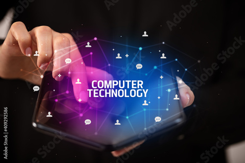 Businessman holding a foldable smartphone with COMPUTER TECHNOLOGY inscription, new technology concept