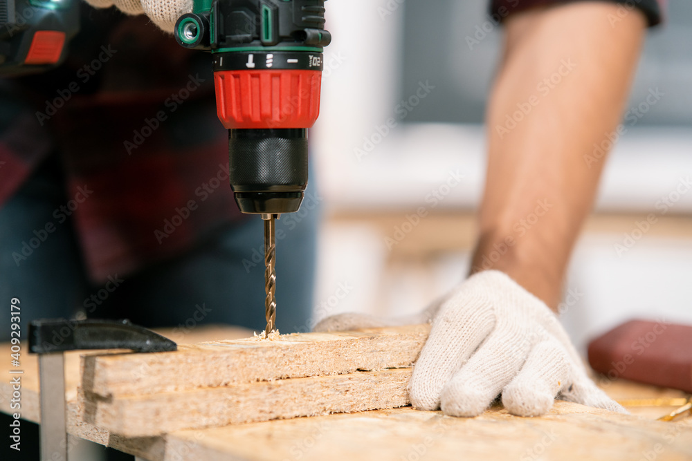 Carpenter drills a hole with an electrical drill Carpenter drills a hole with an electrical drill