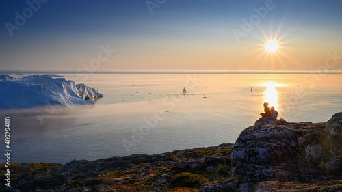 woman in glasses with son sitting on the rocks above the glacial bay