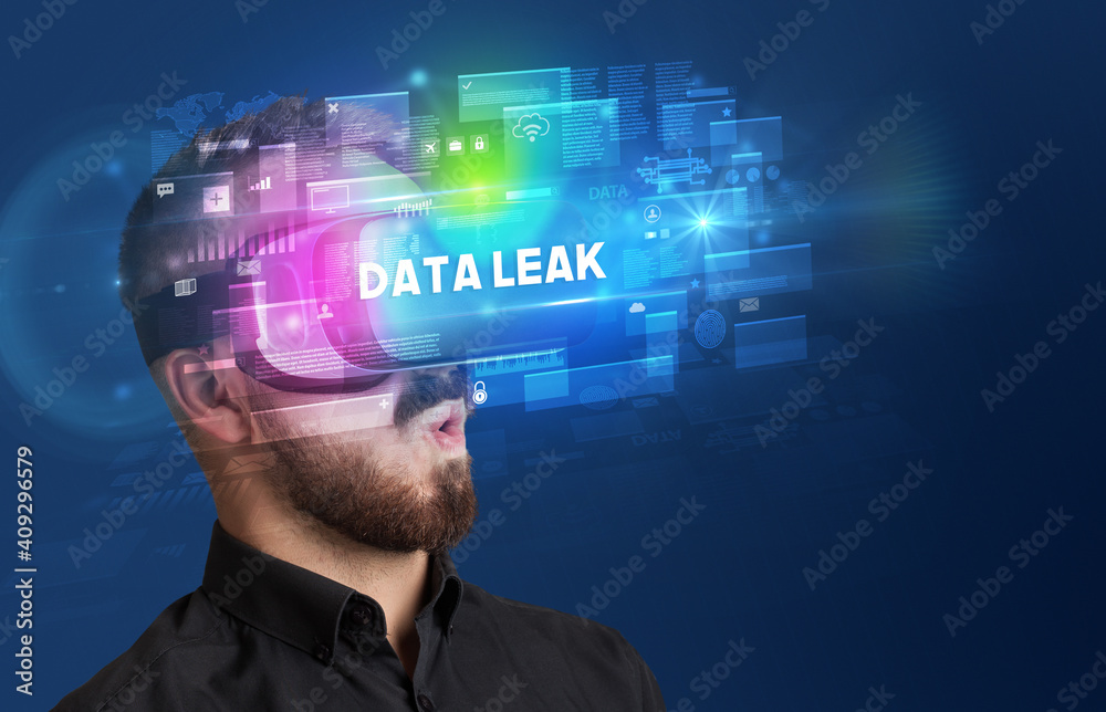Businessman looking through Virtual Reality glasses with DATA LEAK inscription, innovative security concept Businessman looking through Virtual Reality glasses with DATA LEAK inscription, innovative security concept