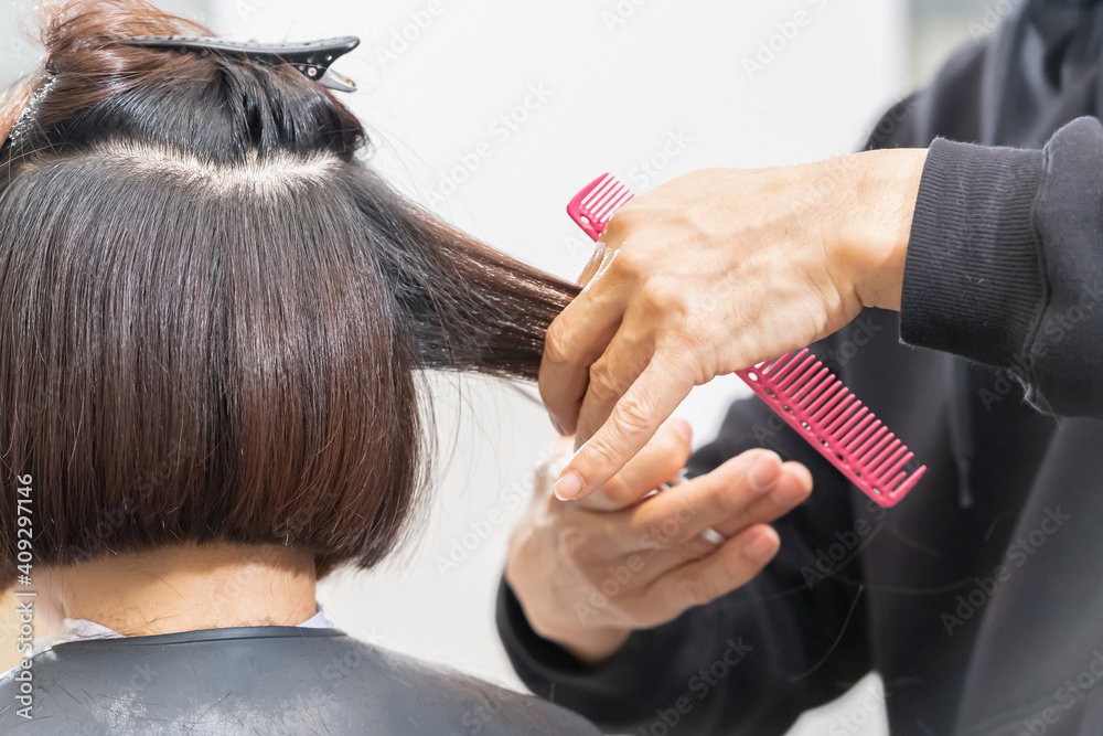 Naklejka premium ヘアサロンで髪の毛をカットする美容師の手元