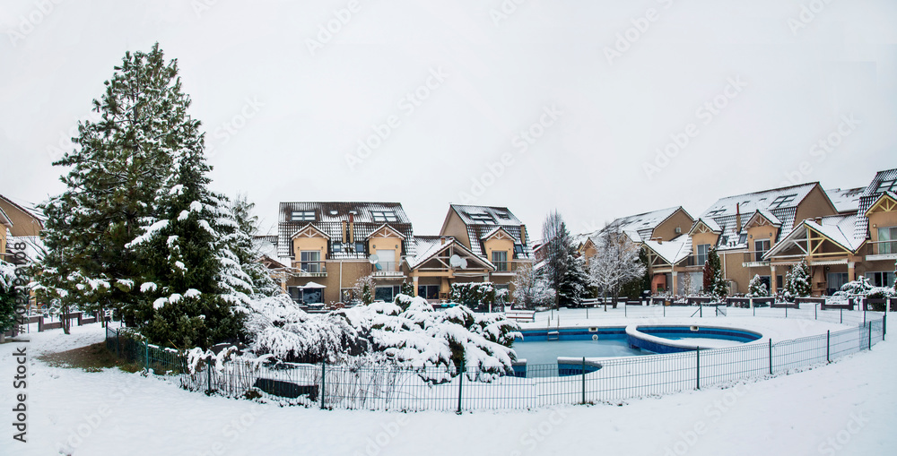 Obraz premium Snow covered yard with a pool in a beautiful neighborhood in Bucharest. Christmas background. Cold temperature, winter time