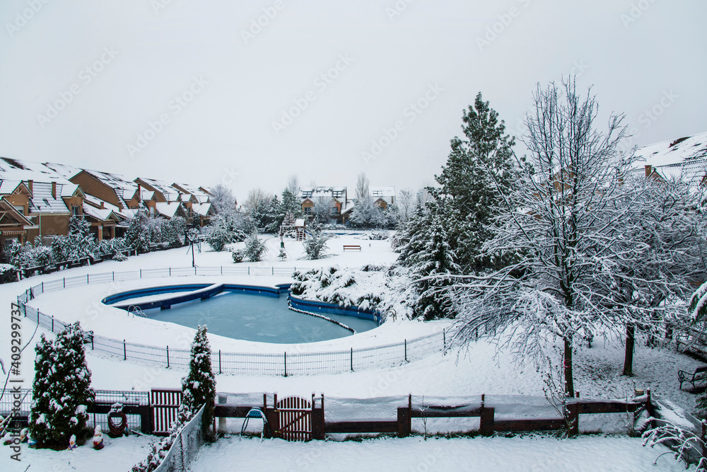 Snow covered yard with a pool in a beautiful neighborhood in Bucharest. Christmas background. Cold temperature, winter time