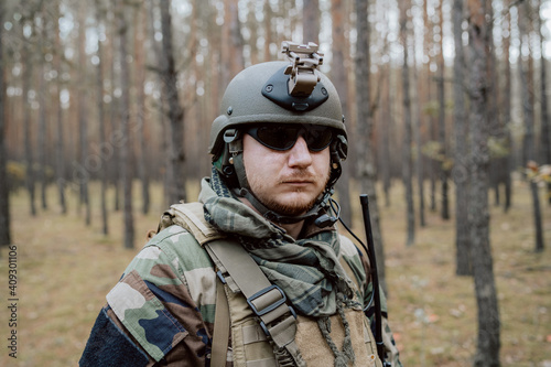 Portrait of a middle-aged bearded soldier in a Woodland military uniform and helmet, with headphones on his head. © ABCreative