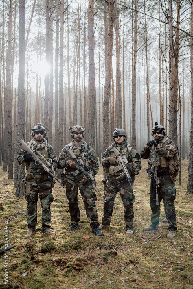 Portrait of a middle-aged bearded soldiers in a Woodland military uniform and helmet, with headphones on his head holding a rifle. Portrait of a middle-aged bearded soldiers in a Woodland military uniform and helmet, with headphones on his head holding a rifle.