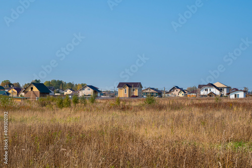Cottage village. Autumn view of a modern cottage village in a dry yellow field.