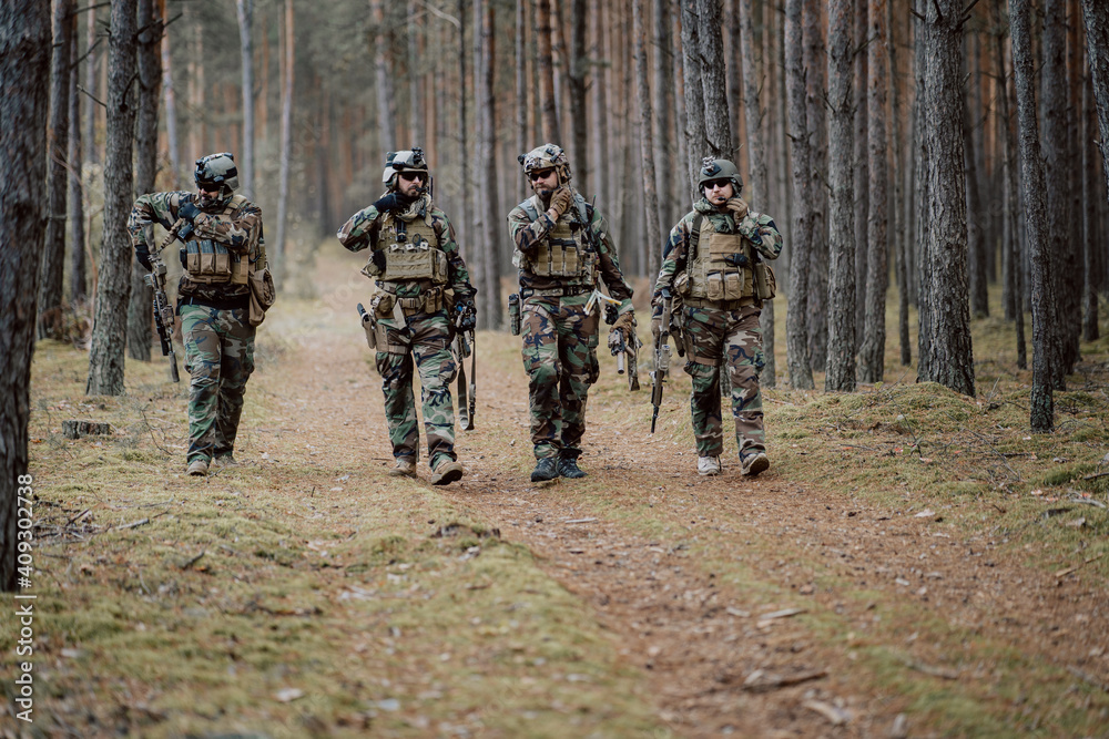 Fully equipped soldiers in camouflage uniform returning from reconnaissance in a pine forest