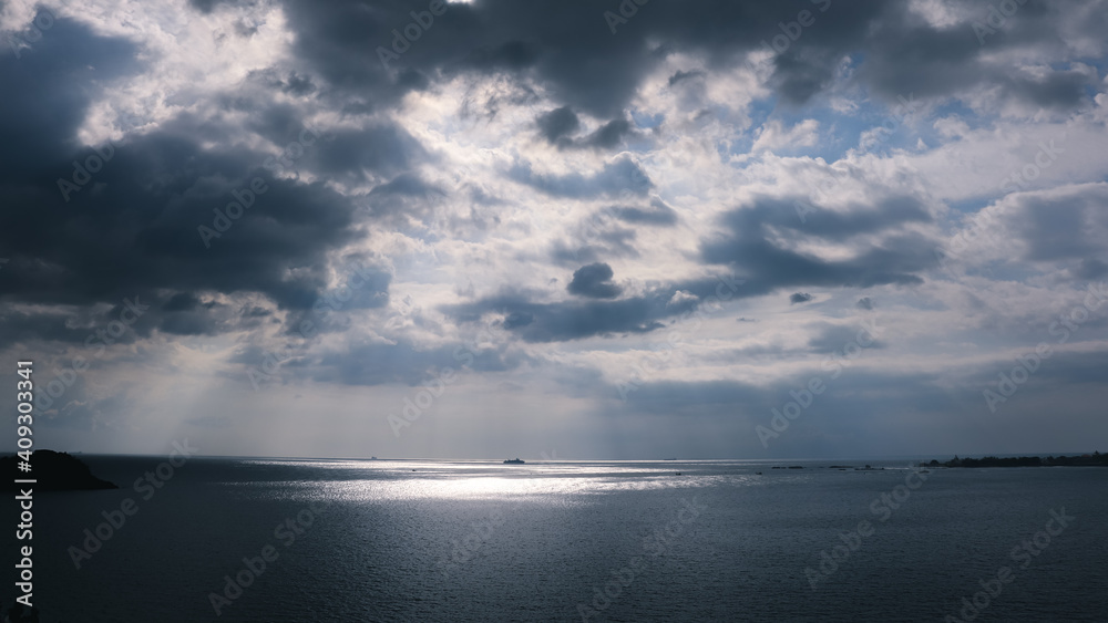 Sun rays coming out through the clouds and hitting the horizon, ocean and dramatic cloudscape,