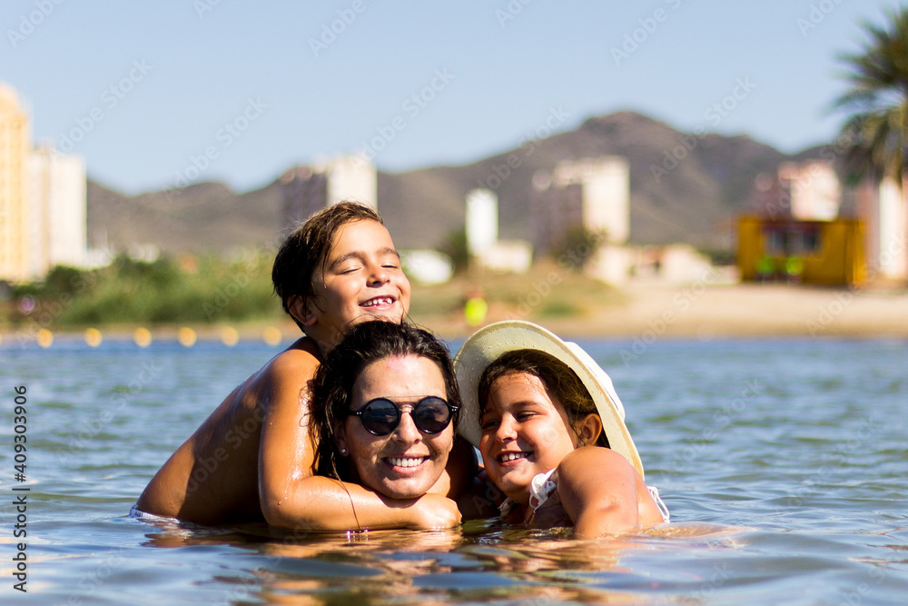 Fototapeta premium mother embracing her children in the sea