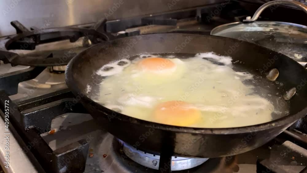 Poached Eggs being cooked in a pan on a gas stove in a dirty grunge kitchen. With slow-motion footage. Poached Eggs being cooked in a pan on a gas stove in a dirty grunge kitchen. With slow-motion footage.