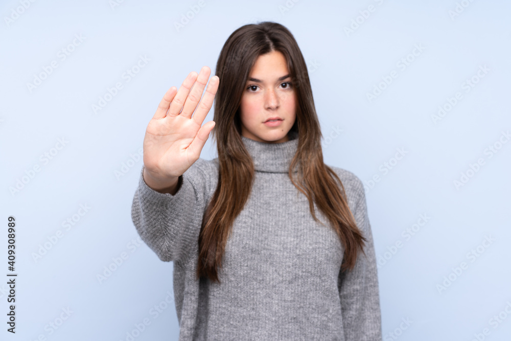 Teenager Brazilian girl over isolated blue background making stop gesture Teenager Brazilian girl over isolated blue background making stop gesture