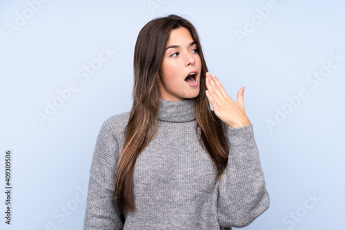 Teenager Brazilian girl over isolated blue background yawning and covering wide open mouth with hand