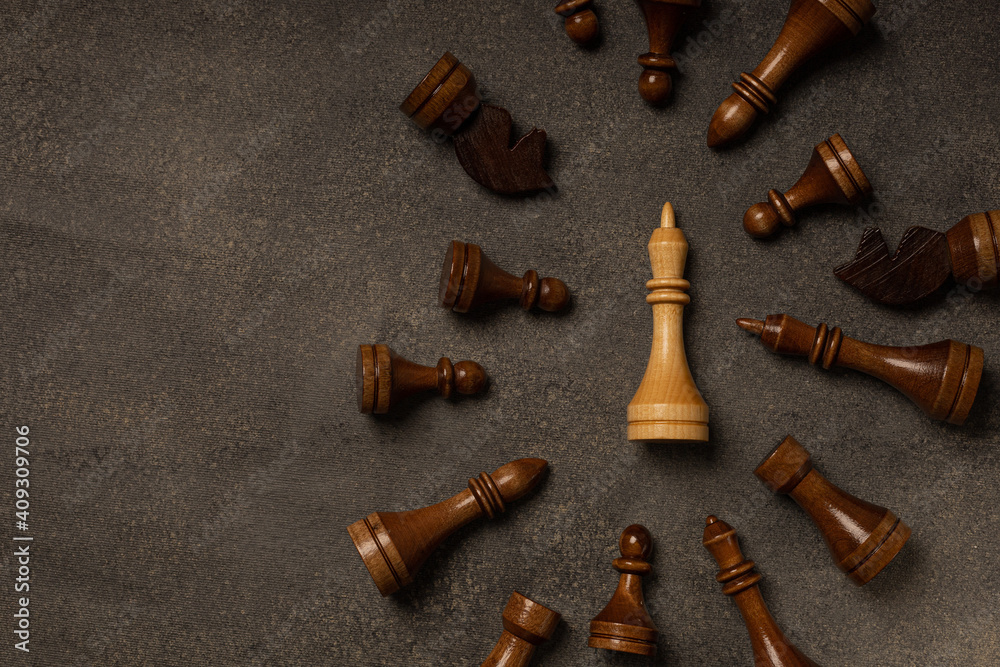 White king among black chess pieces on dark background White king among black chess pieces on dark background