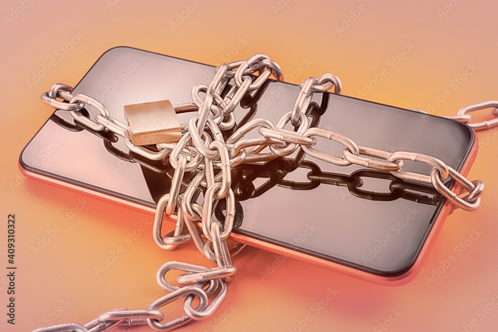Smart phone in chain with lock on orange background with selective focus