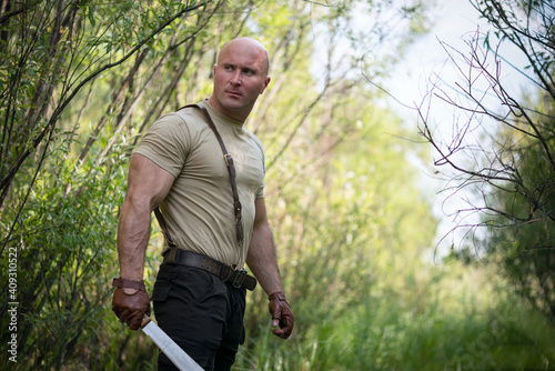Strong adventurer man with a sharp machete in the forest concept. photo