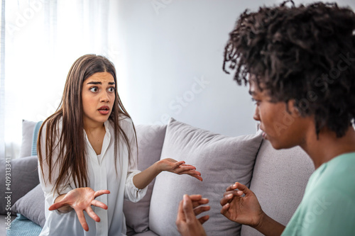 Girls quarrel. Women talking loudly about something. Friends arguing on sofa at home. Two female friends arguing with each othe. Friendship, quarrel, female disagreement, copy space