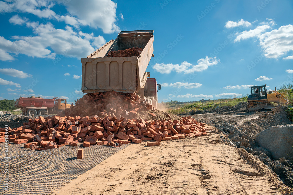 Fototapeta premium truck unloads old brick on a road under construction to a new construction site