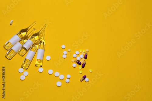 Vaccination against the Covid19 virus. Ampoules, tablets for treatment. Prevention concept. Yellow background.
