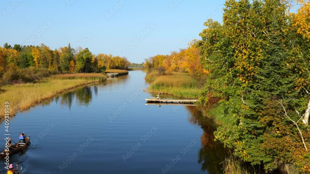Mississippi River and two canoes head north toward Bemidji Minnesota near highway 2 with zoom in. Beautiful autumn colors in the trees along the river, a few miles from the source at Lake Itasca Mississippi River and two canoes head north toward Bemidji Minnesota near highway 2 with zoom in. Beautiful autumn colors in the trees along the river, a few miles from the source at Lake Itasca