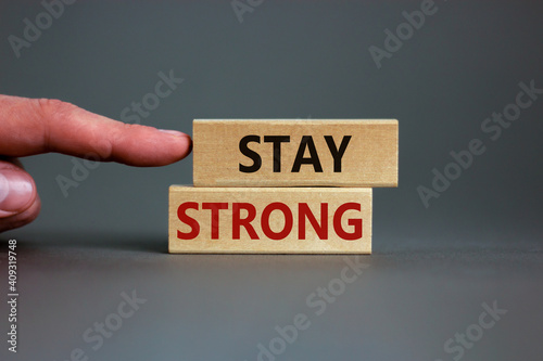 Stay strong symbol. Wooden blocks with words 'stay strong'. Beautiful grey background. Businessman hand. Copy space. Motivational, business and stay strong concept.