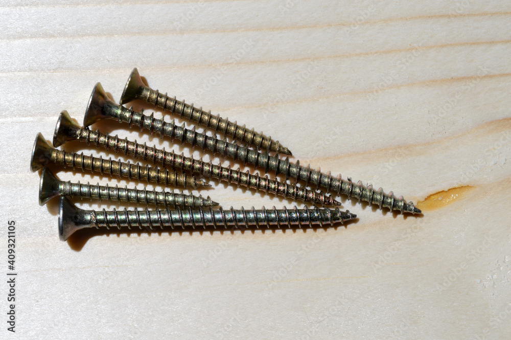 several yellow self-tapping screws on a wooden background. close-up. several yellow self-tapping screws on a wooden background. close-up.
