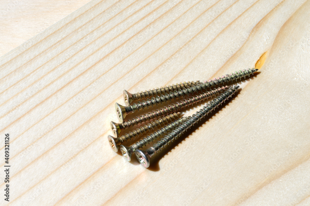 several yellow self-tapping screws on a wooden background. close-up. several yellow self-tapping screws on a wooden background. close-up.