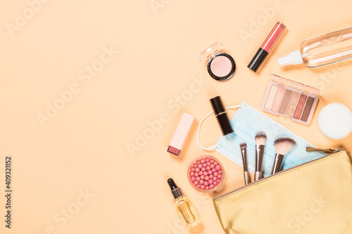 Cosmetic bag with make up products and face mask. New normal concept. Flat lay image with copy space.