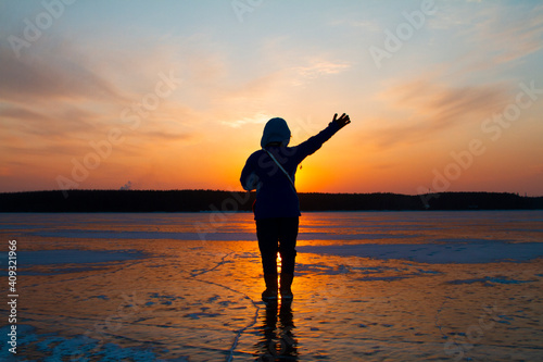 Silhouette of a person on the frozen lake in sunset.
