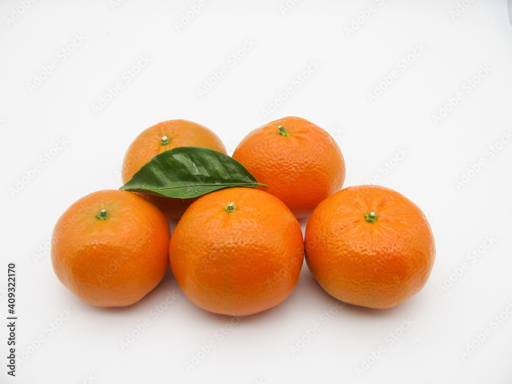 Five orange fresh tangerines and a green leaf on a white background. Five orange fresh tangerines and a green leaf on a white background.