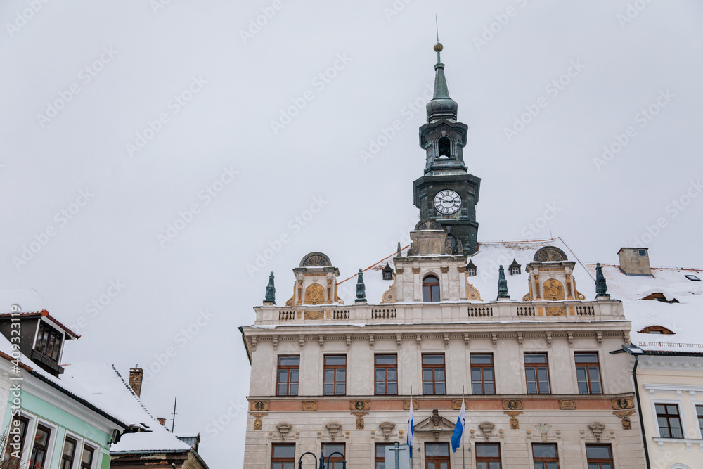City hall with clock tower on T. G. Masaryk Square, baroque, renaissance and Art Nouveau historical buildings under snow in winter day, Ceska Lipa, North Bohemia, Czech Republic