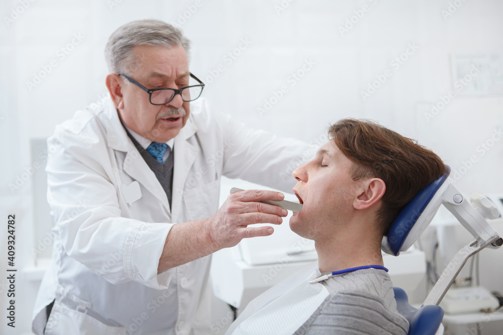 Experienced senior dentist examining teeth of a patient Experienced senior dentist examining teeth of a patient