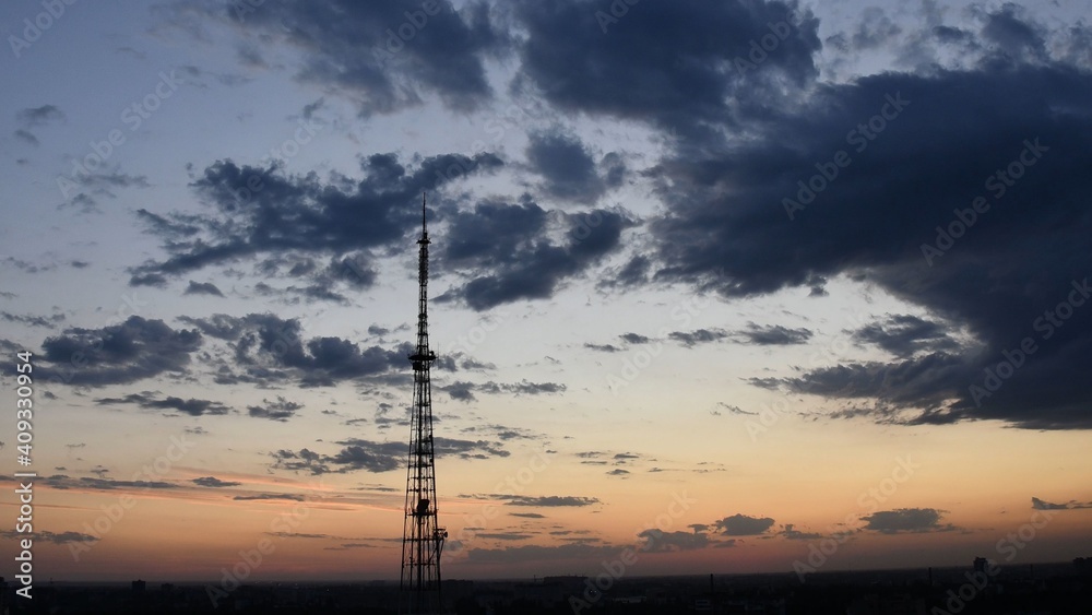 Cloudscape with industrial communication tower and dusk purple clouds. Dark dramatic sky sundown