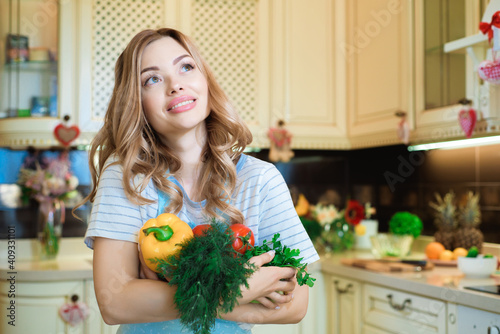 Healthy eating lifestyle concept portrait of beautiful young woman with vegetables in her hand at home in the kitchen