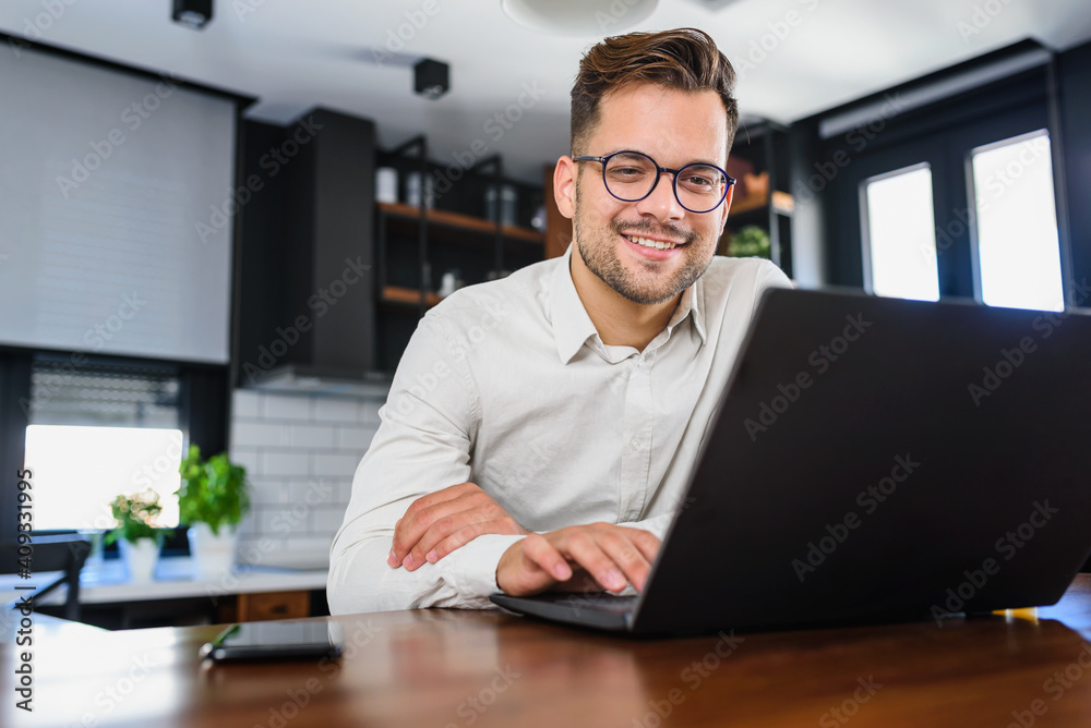 Young man holding credit card sitting in front of laptop computer at home paying for online order. People lifestyle modern technologies and e-commerce concept
